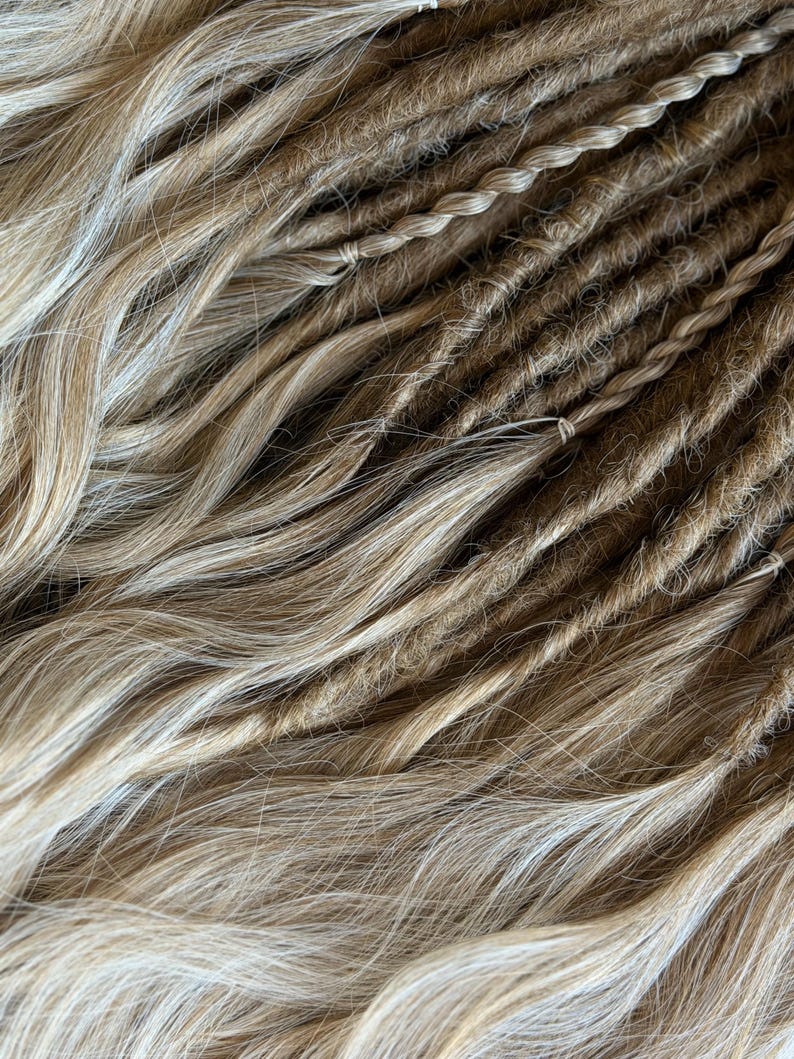 Full bundle of handmade blonde DE dreads and waves displayed on wicker background