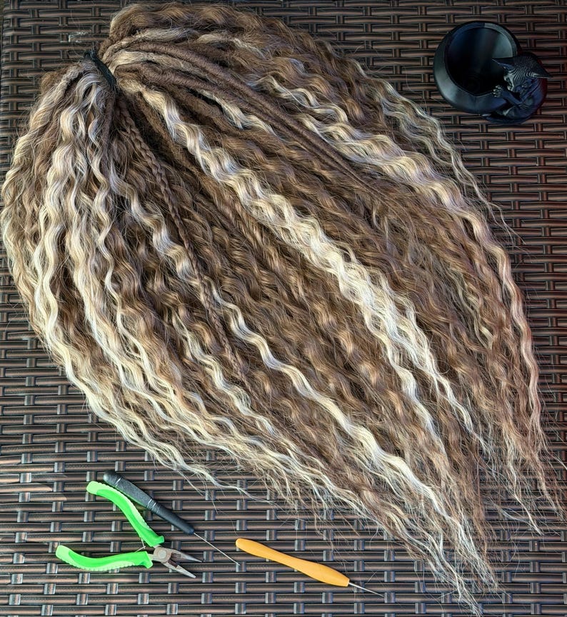 Flat lay of handmade blonde brown push-up curly DE dreadlock set on woven rattan surface