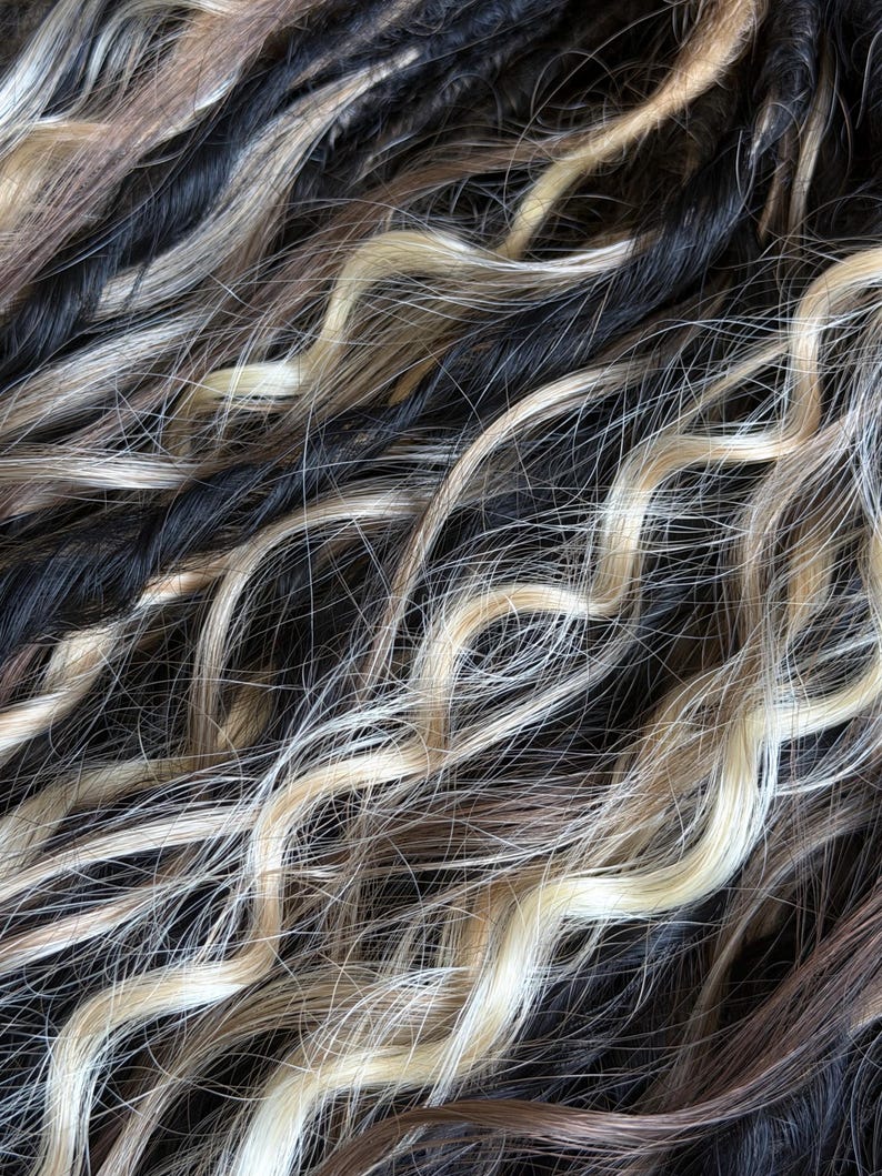 Close up of soft black and ash blonde wavy dreadlock texture handmade set